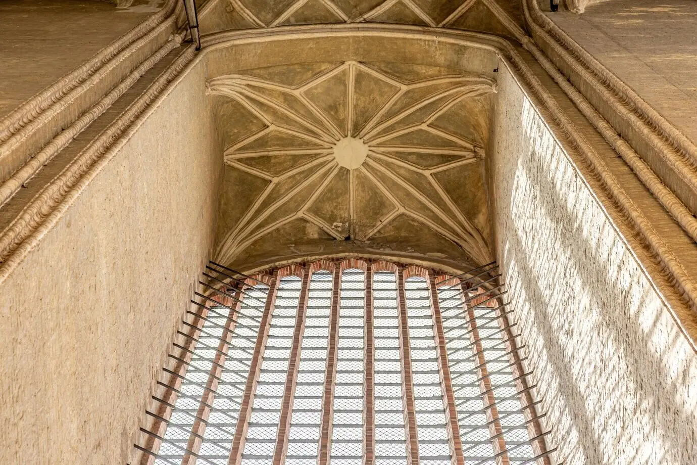 A Gothic vault with stone patterns, historic cathedral art, and light playing on the walls.