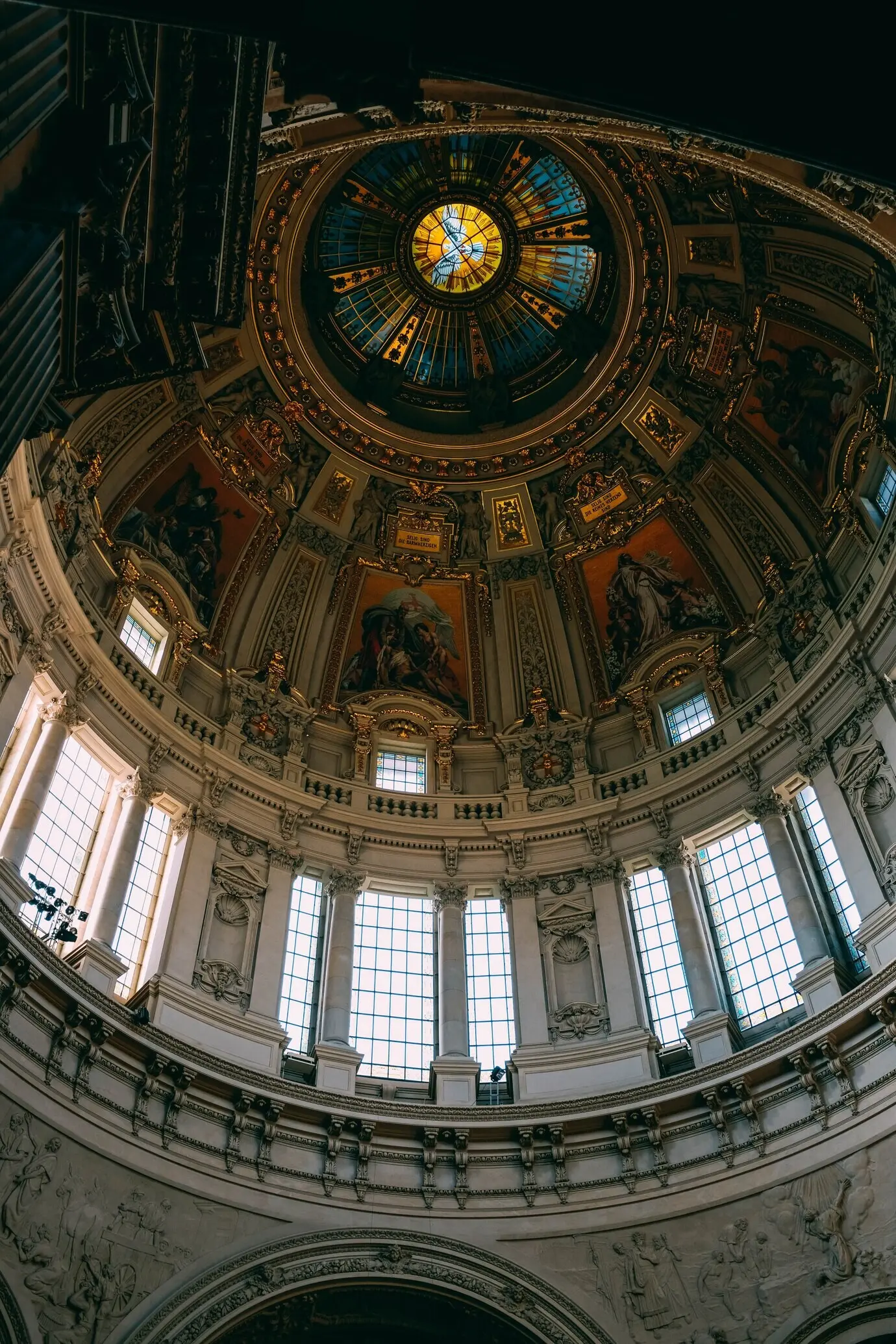 A low-angle shot of the beautiful ceiling, windows, and paintings in an old building