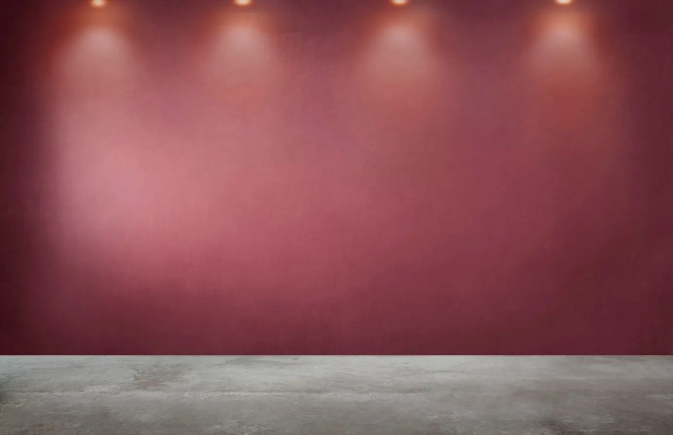A red wall and a row of spotlights in an empty room.